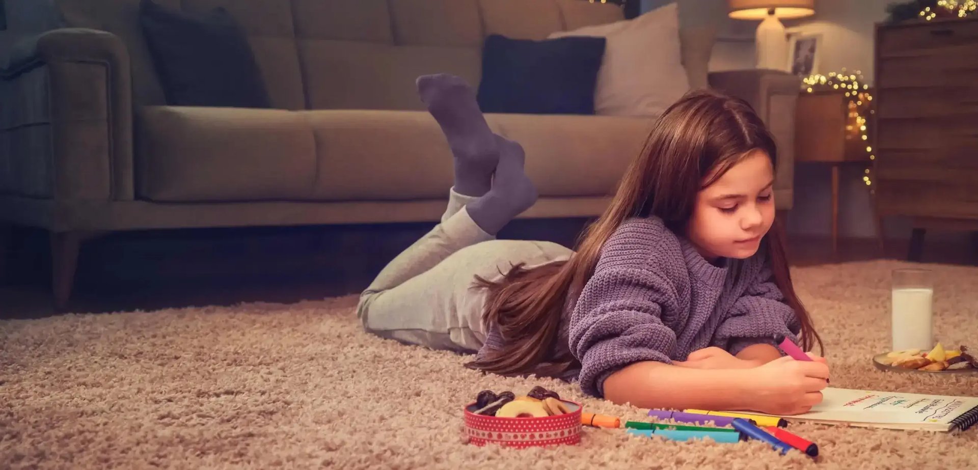 Ein Mädchen liegt am Boden und zeichnet. 