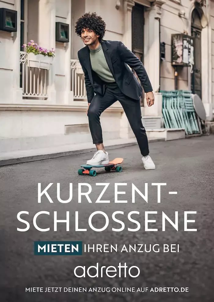 Junger Mann mit Anzug auf Skateboard