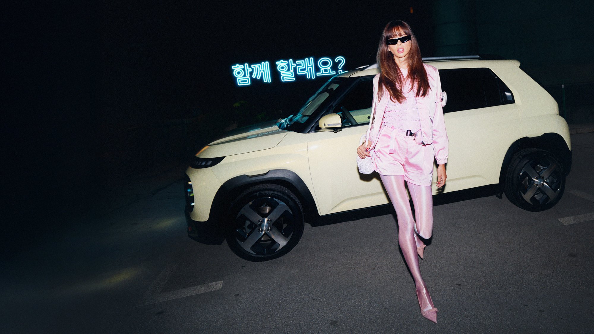 Eine Frau steht vor einem Hyundai INSTER.